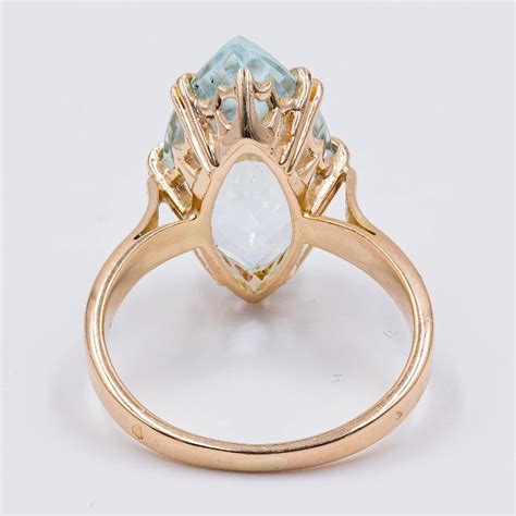 Schéma détaillé de la bague ancienne avec aigue-marine, mettant en évidence la monture en or 14 carats, le sertissage à griffes, le chaton ajouré et les épaules fendues.