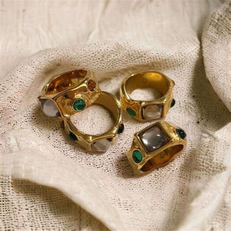 Photographie de plusieurs bagues vintage ornées de différentes pierres précieuses, dont une aigue-marine, présentées sur un fond élégant.