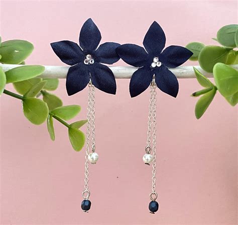 Illustration de différentes boucles d'oreilles bleu marine : pendentif sequin, feuille, nounours.