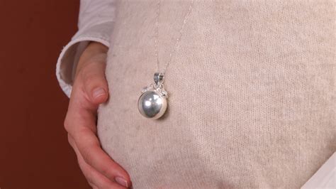 Photo d'une femme enceinte portant un bola de grossesse, le pendentif reposant sur son ventre arrondi.