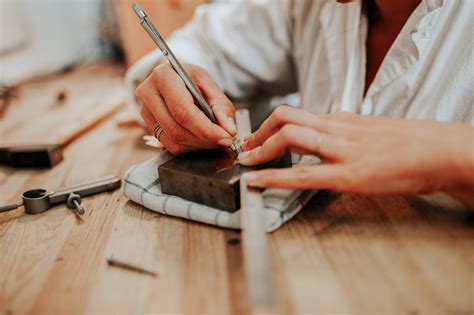 Photographie de différentes étapes de la fabrication d'un bijou : esquisse, travail du métal, sertissage de pierres.