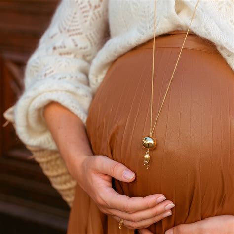 Illustration d'une femme enceinte portant un bola de grossesse, avec des symboles angéliques.