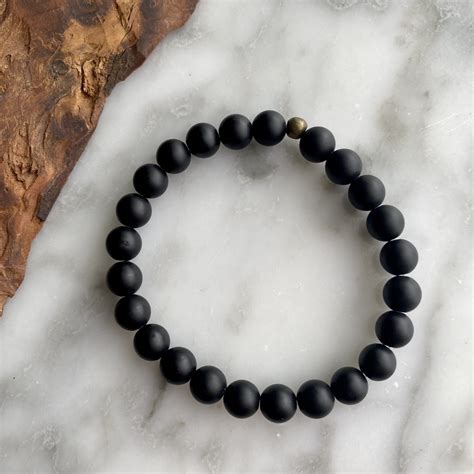 Gros plan sur des perles d'onyx noir mat et un détail de tête de mort en acier