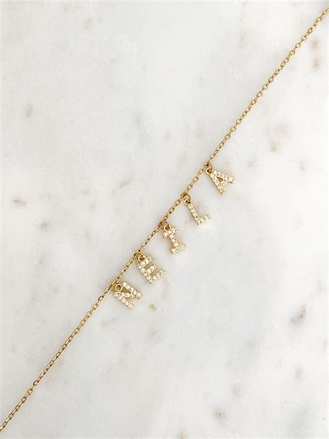 Schéma illustrant un collier prénom vertical avec des lettres disposées en ligne.