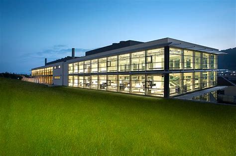 Architecture sobre et transparente de la Manufacture Cartier à La Chaux-de-Fonds, s'intégrant harmonieusement dans le paysage jurassien.