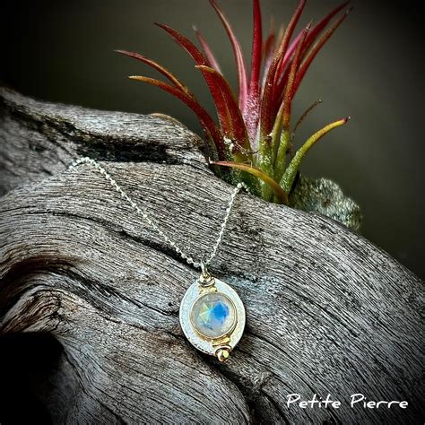 Représentation d'un pendentif avec une pierre de lune aux reflets bleutés et argentés.