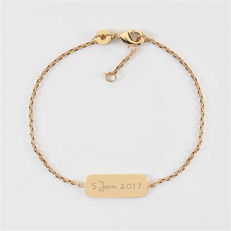 Un bracelet d'identité en or jaune, gravé du prénom et de la date de naissance d'un bébé.
