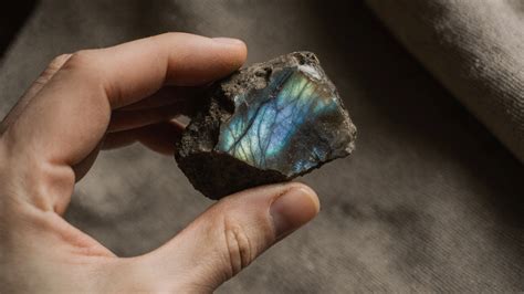 Une main tenant un bracelet en labradorite sous une lumière révélant ses reflets