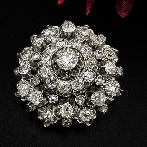 Photographie d'une broche ancienne très ouvragée, sertie de diamants et de perles, de style Louis XVI.
