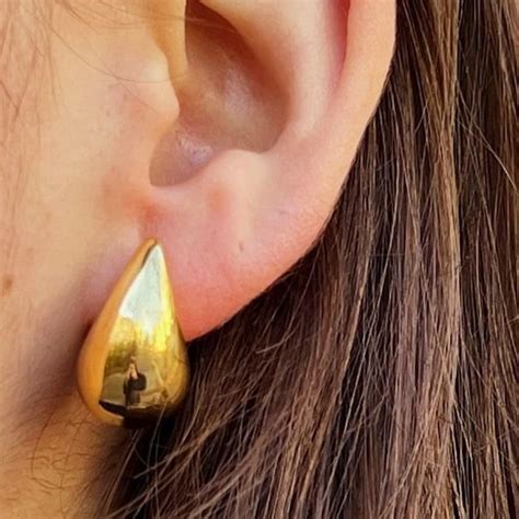Représentation schématique d'une boucle d'oreille en forme de goutte avec un fermoir poussette papillon.