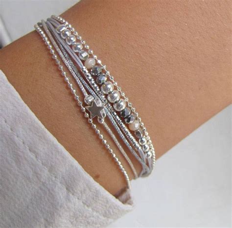Image d'une composition de plusieurs bracelets en argent portés ensemble, incluant des modèles avec pierres et des joncs