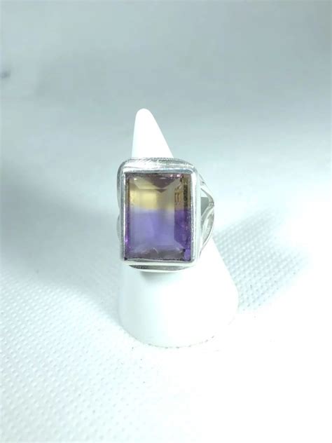 Photographie d'une bague sertie d'une amétrine, mettant en valeur le dégradé de couleurs jaune et violet.