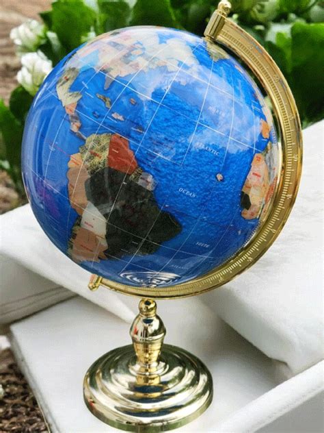 Photographie de différents globes terrestres en pierres semi-précieuses sur divers pieds en laiton