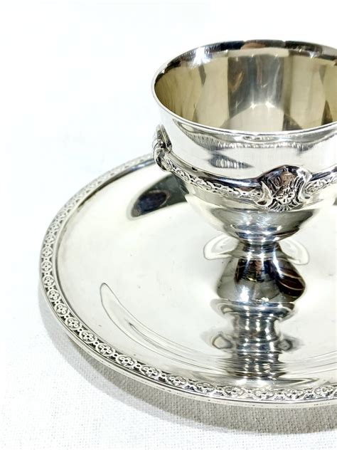 Détail du pied d'un coquetier en argent massif avec godrons, lambrequins et fleurons sur fond amati.