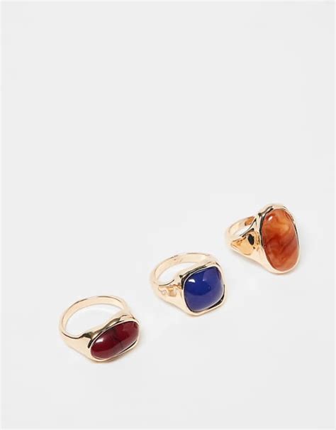 Une sélection de bagues Kenzo ornées de diverses pierres précieuses, mettant en avant les couleurs et les éclats.