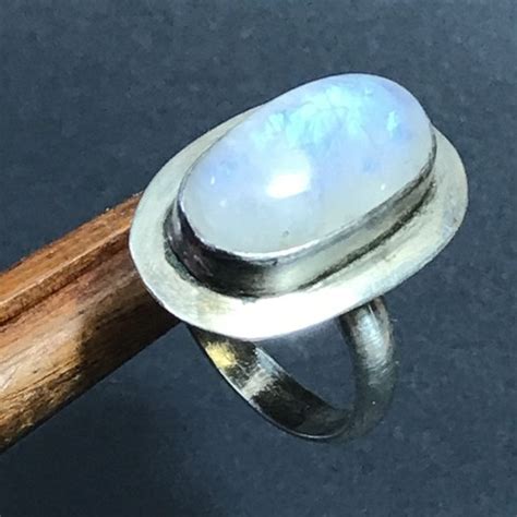 Une bague en argent sertie d'une pierre de lune, mettant en valeur l'éclat bleuté.