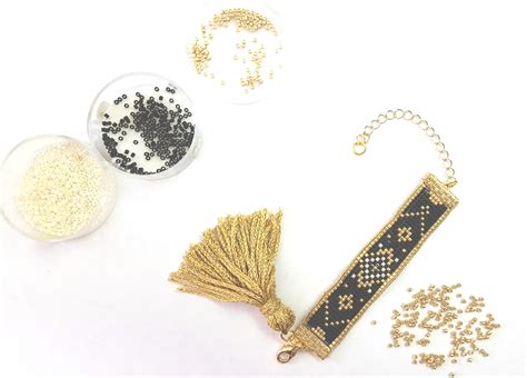 Gros plan sur le pompon fait main du bracelet, avec détails des fils noir et doré