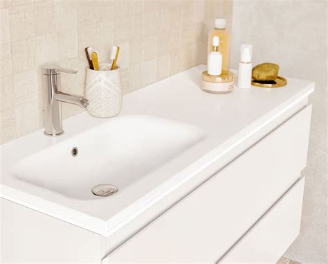 Détail d'un plan vasque en matériau de synthèse blanc brillant avec robinetterie moderne