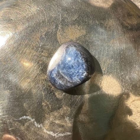 Photographie d'une pierre roulée de saphir bleu polie, mettant en évidence sa couleur bleue profonde et sa surface lisse.