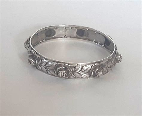 Gros plan sur un bracelet en argent massif orné d'une tête de lion sculptée, mettant en valeur les détails et la brillance du métal.