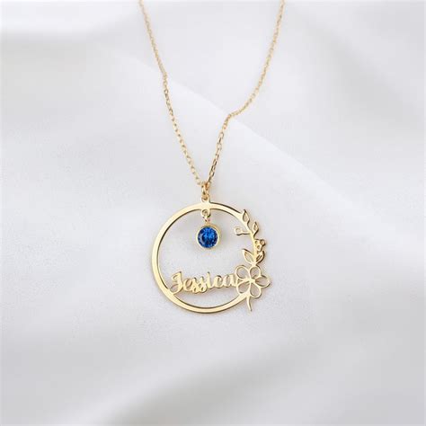 Gros plan sur un collier personnalisé avec un disque martelé, une pierre de naissance bleue et une gravure délicate.