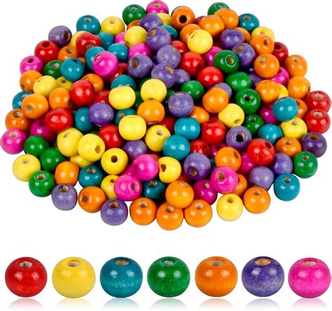 Photographie montrant le détail de perles en bois peintes en blanc avec des fleurs séchées et de petites perles rondes assorties