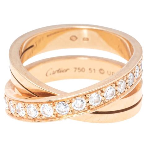 Photographie de la bague Cartier en or rose 18 carats avec diamants, mettant en valeur le diamant central taille émeraude et les diamants d'accentuation.