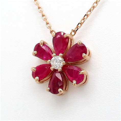Photographie macro d'un pendentif fleur en or rose avec un rubis central.