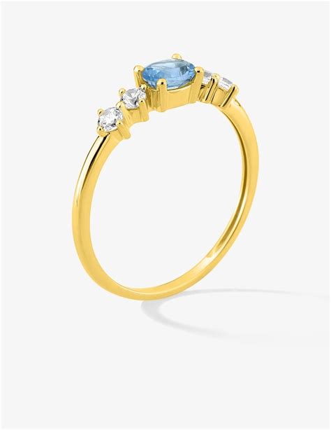 Image d'une bague en or avec une topaze bleue ovale et des diamants sertis de chaque côté.